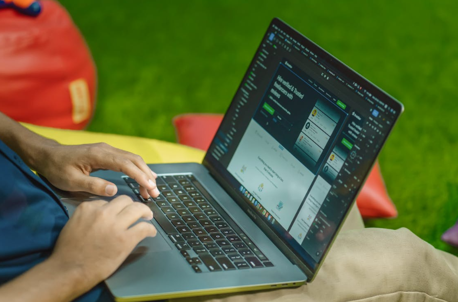 Person working on laptop with betting platform interface outdoors